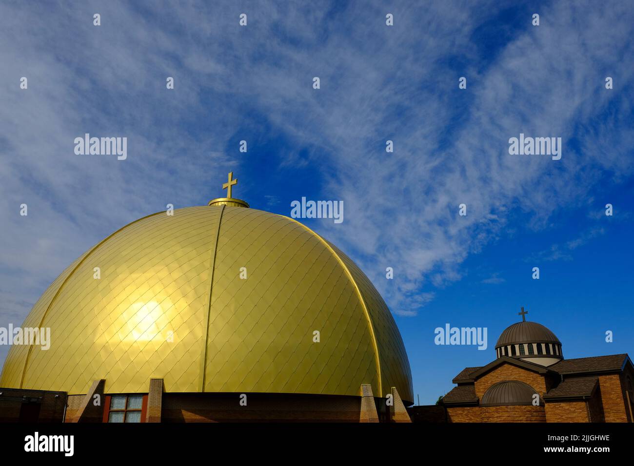 Cúpula dorada en una iglesia cristiana con la cruz y las nubes azules del cielo en el fondo Foto de stock