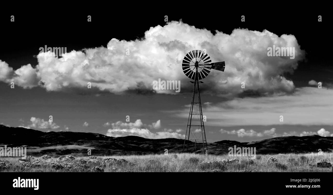 Molino de viento en la ladera en el campo América rural con cielo y nubes negro y blanco Foto de stock