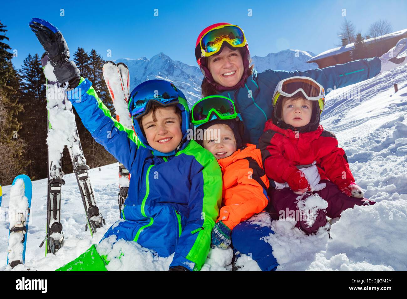 Los niños y la madre, la familia en vacaciones de esquí se sientan juntos en la nieve Foto de stock