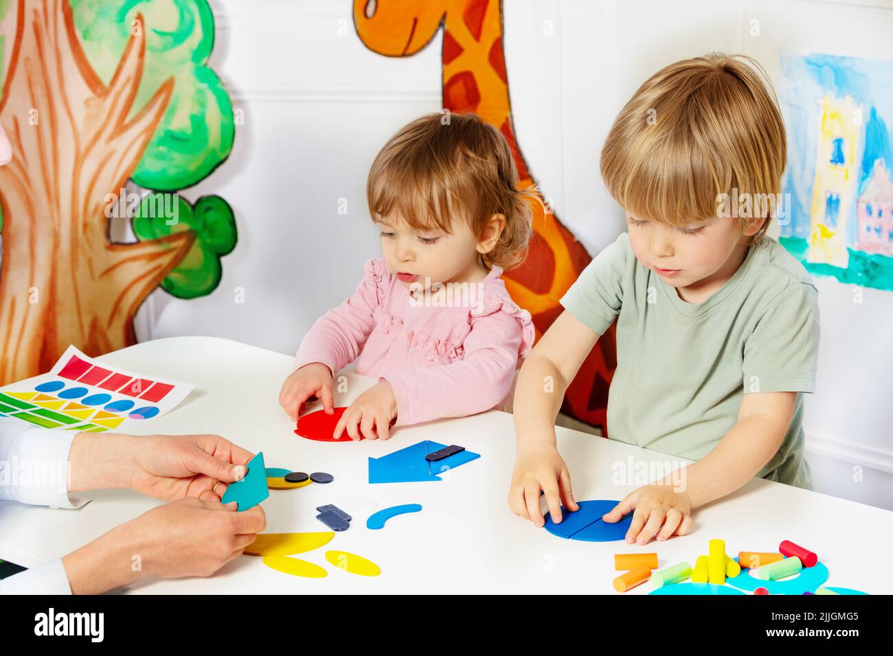 Un niño y una niña juntaron formas sobre la mesa en el jardín de infantes Foto de stock