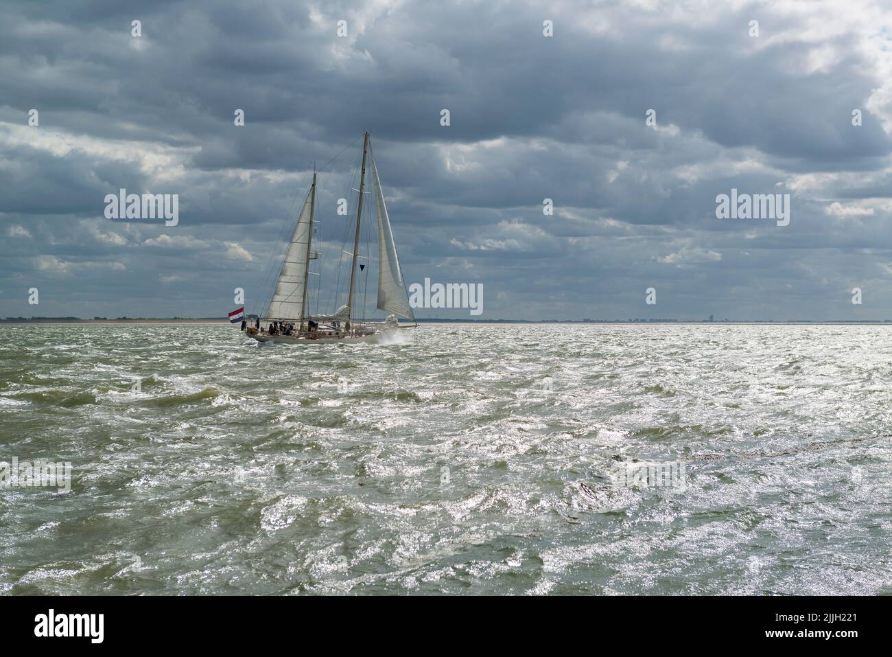 Un barco de vela de dos maestros en el estuario del oeste de Scheldt con tiempo ventoso y nublado. Provincia de Zeeland, Países Bajos Foto de stock
