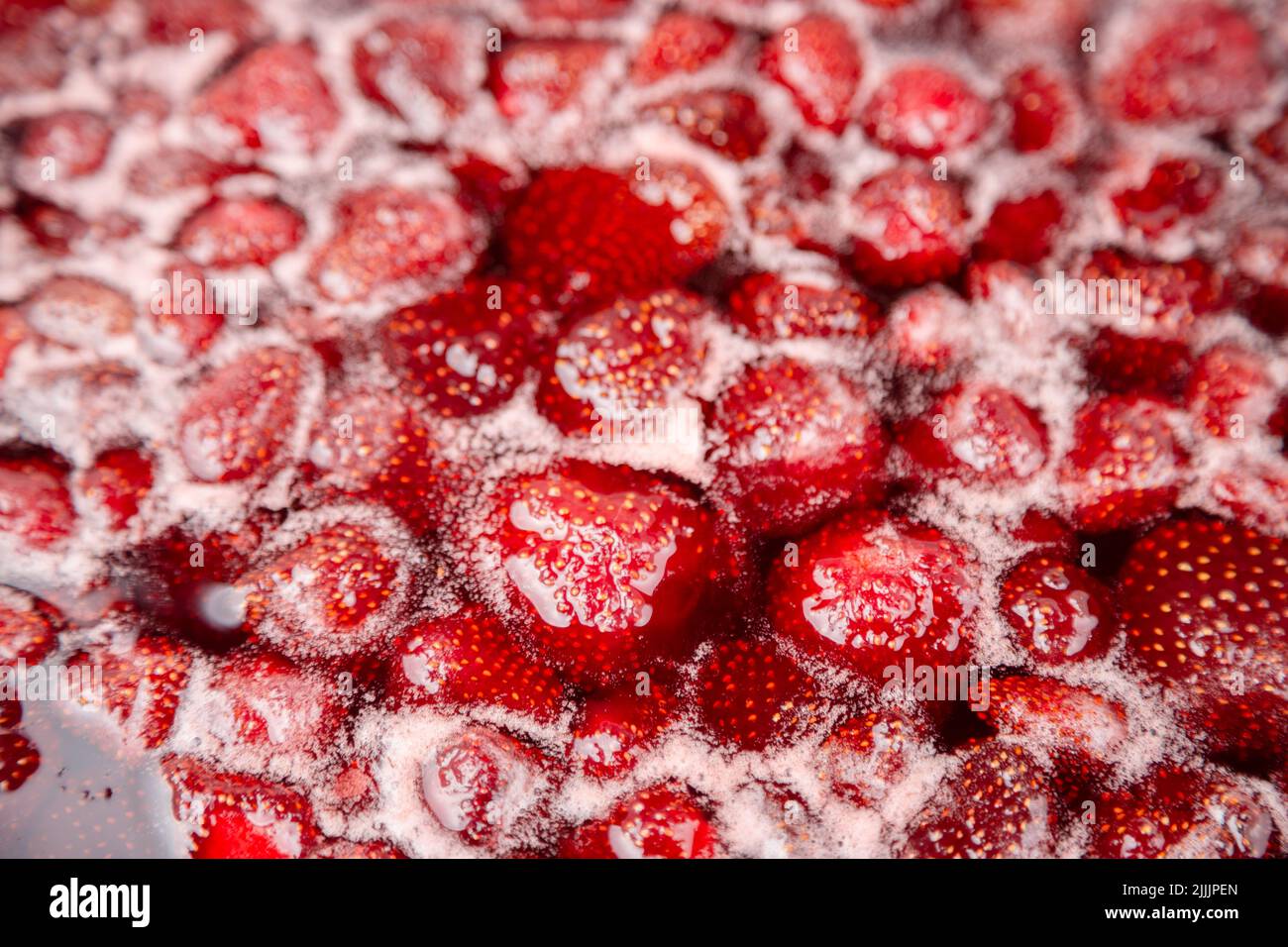 PRIMER PLANO: Mermelada de fresa. Haga una mermelada de fresa. Hierva las fresas en la sartén. Proceso de cocción, hervir bayas para enlatar. Alimentos dulces saludables. Cocinar mermelada de fresa de cerca. Foto de stock