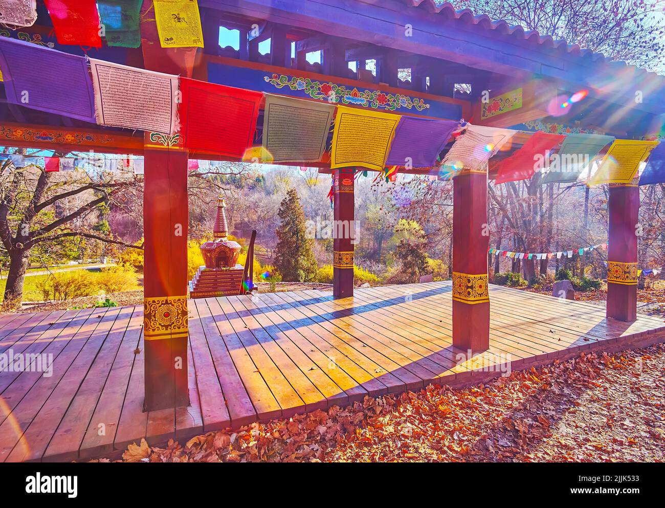 El soleado mediodía del otoño en el jardín tibetano con banderas budistas, cenador para la meditación y coro en el fondo, el jardín botánico de Kiev, Ucrania Foto de stock