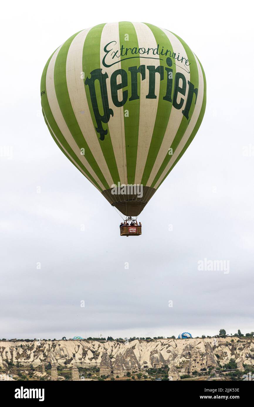 GOREME/TURQUÍA - 29 de junio de 2022: Un globo aerostático con letras Perrier vuela sobre la ciudad de goreme. Turquía. Foto de stock