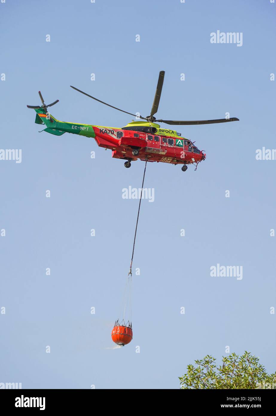 Helicóptero de INFOCA llevando un balde de agua para caer sobre un incendio forestal, Mijas, España. Foto de stock