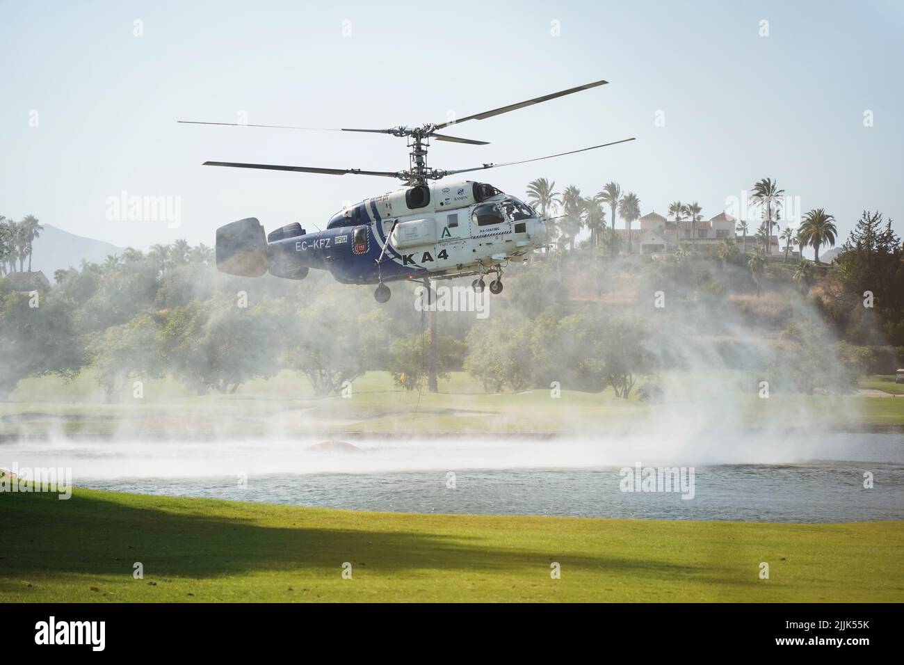Helicóptero pesado de INFOCA recogiendo agua de un estanque artificial en un campo de golf, para caer en un incendio forestal, Mijas, España. Foto de stock