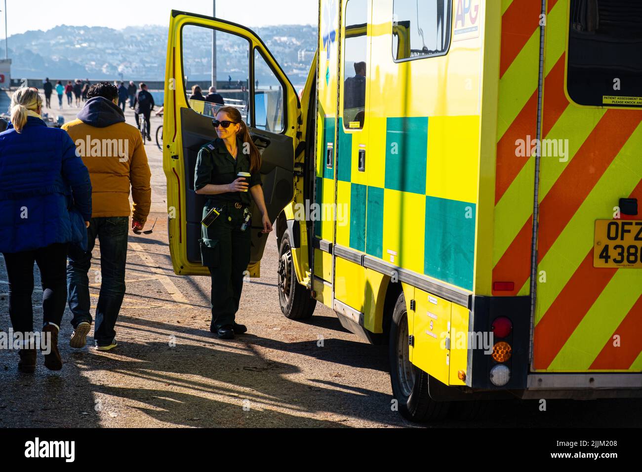 Paramédicos del NHS en pausa para el almuerzo con ambulancia. En uniforme y en espera en caso de emergencia. Ambulancia de alta visibilidad. Foto de stock