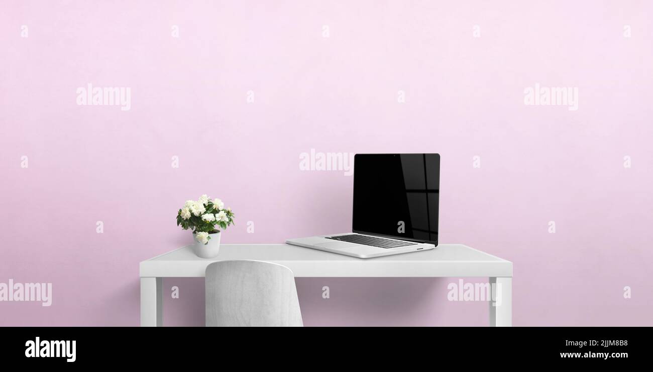 Pequeño escritorio con computadora portátil y flores. Pantalla de portátil en blanco para la presentación de páginas Web. Espacio de copia en pared rosa Foto de stock