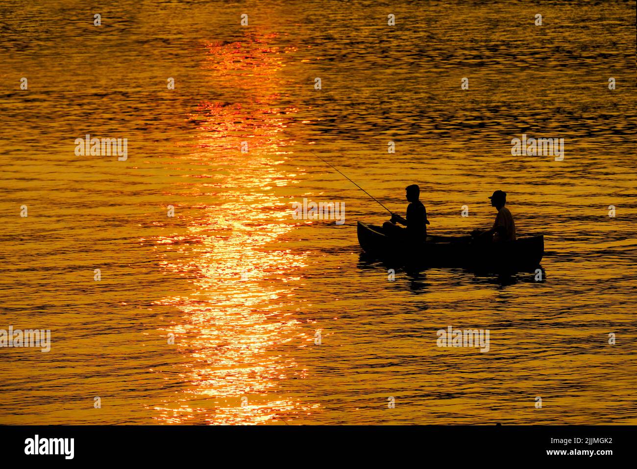 Dos 2 personas en canoa pescando en el lago o el río al atardecer recreando el amanecer Foto de stock