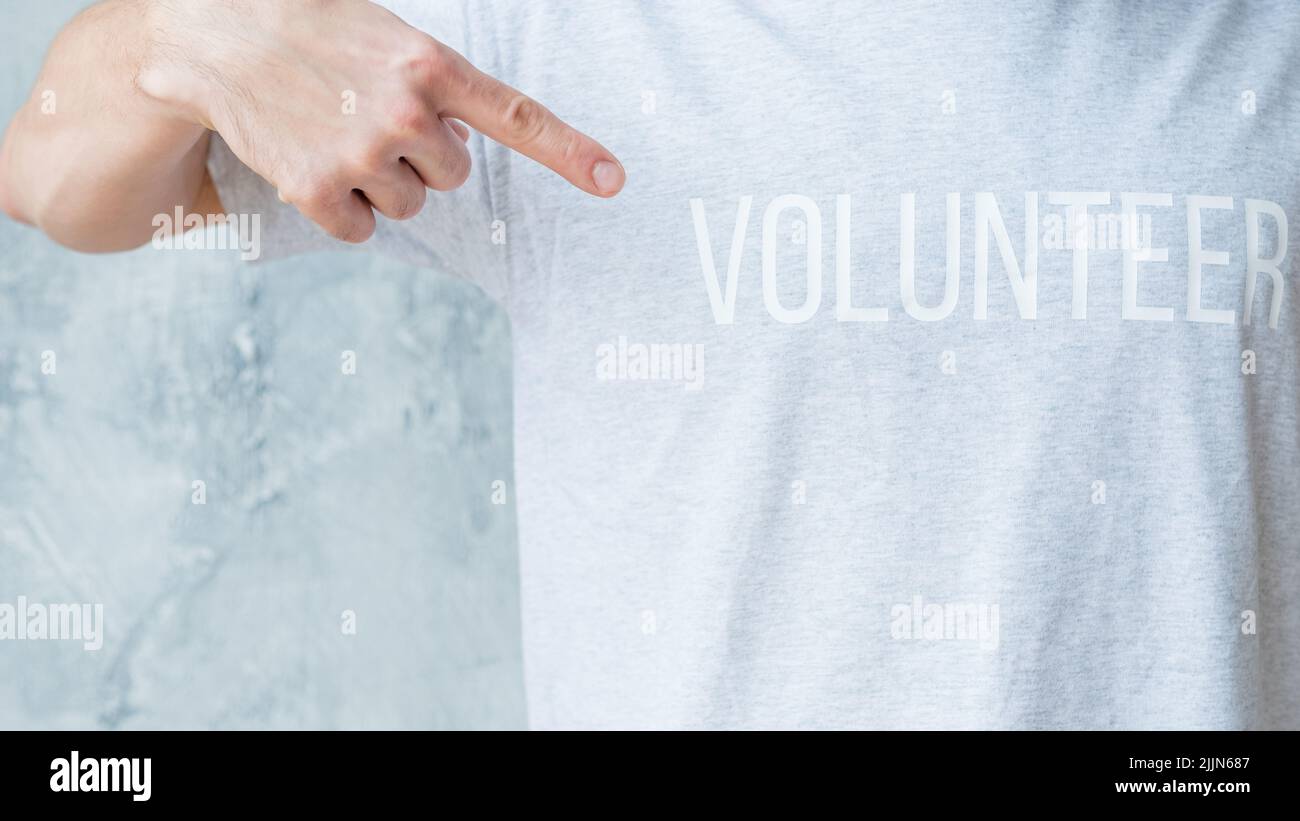 hombre camiseta voluntario punto índice dedo comunidad Foto de stock