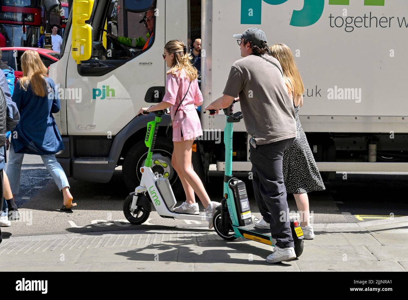 Londres, Reino Unido - Junio de 2022: Gente que monta scooters eléctricos junto al tráfico en Oxford Street Foto de stock