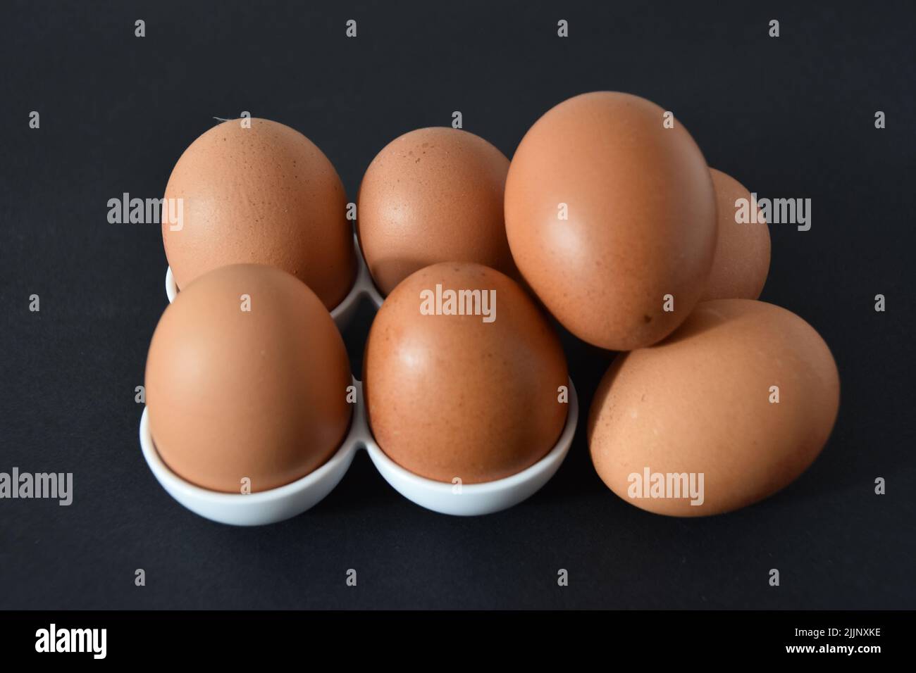 Un primer plano de los huevos de pollo marrones sobre fondo gris oscuro. Foto de stock