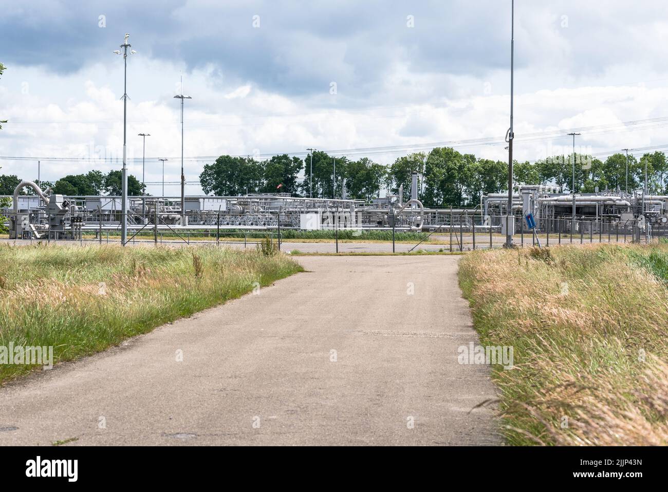 Pozos, tuberías y válvulas en un sitio de extracción de gas natural que forma parte del campo de gas de Groningen en un día nublado de verano Foto de stock