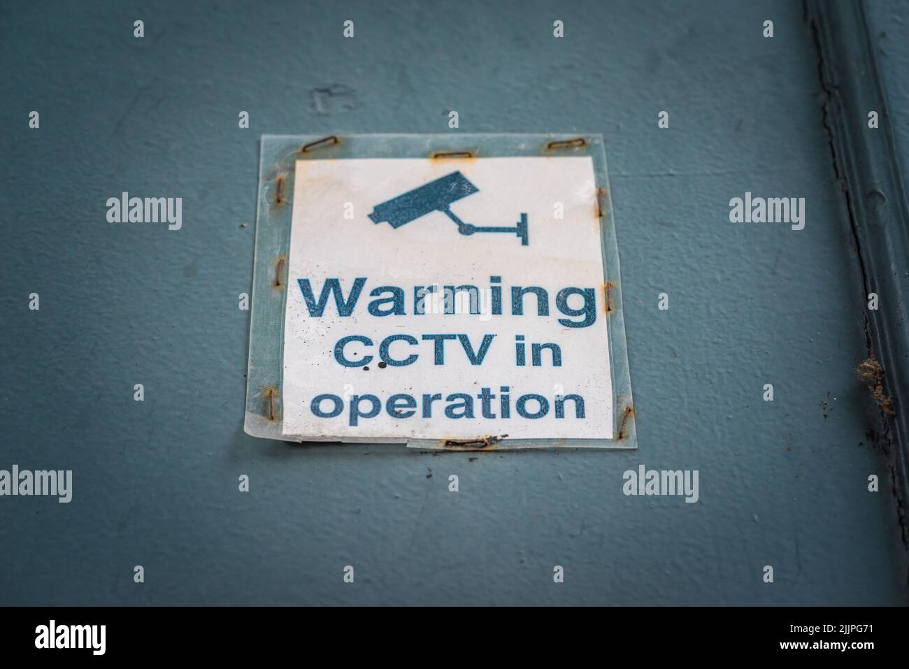 Advertencia: CCTV en funcionamiento, señalización antigua desgastada en una puerta en Inglaterra, Reino Unido Foto de stock