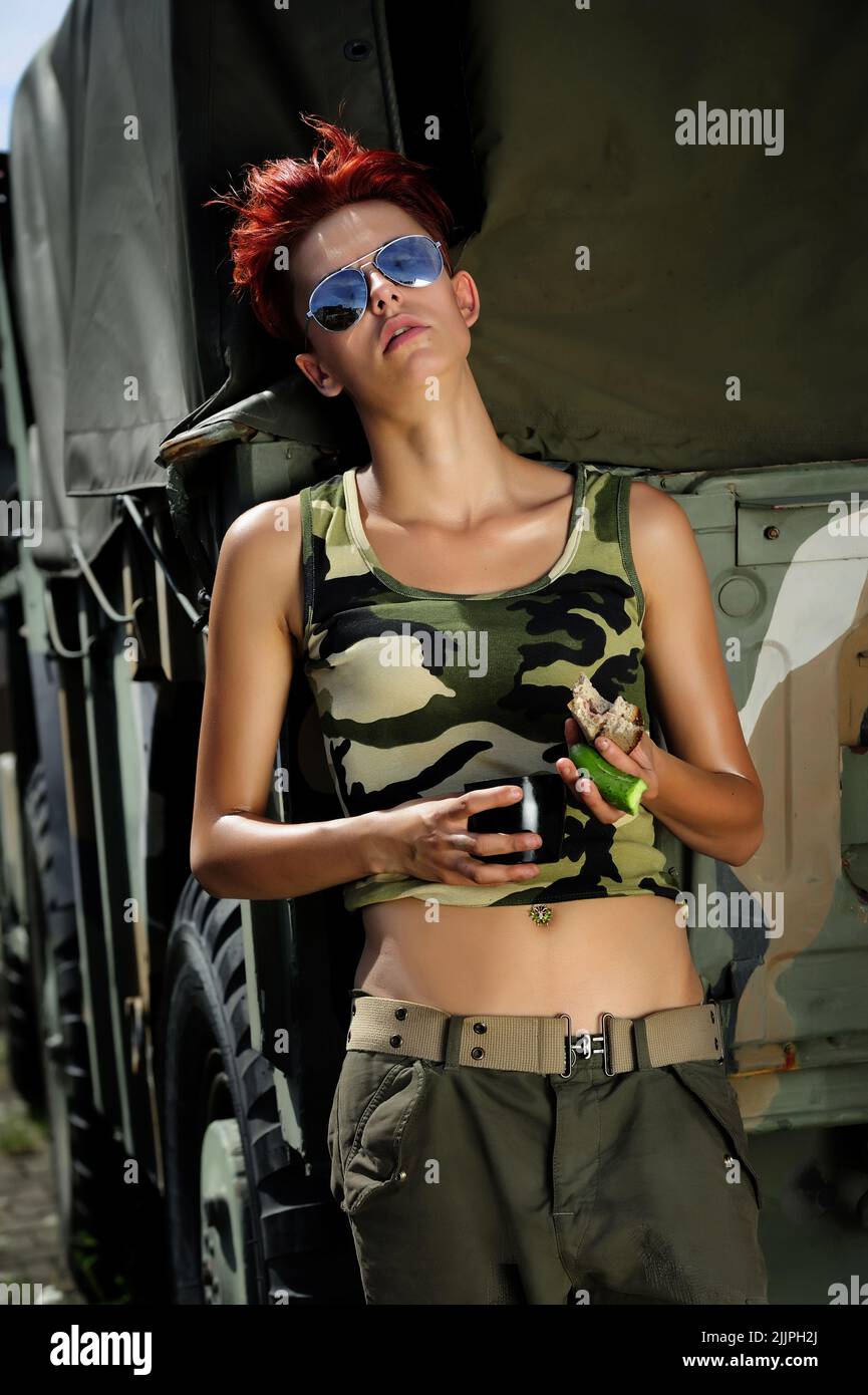 mujeres en el ejército, mirando, militares, soldado, mujeres, chica joven con un traje estilo ejército, ejército, avión, azul, belleza, estilo militar Foto de stock