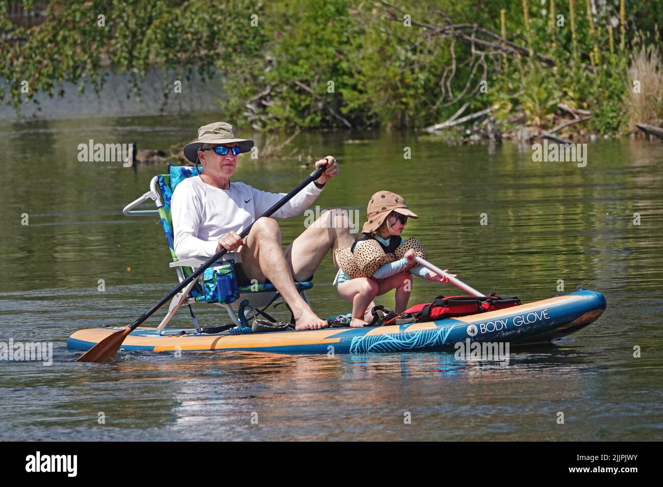 El abuelo y la nieta flotan el río Deschutes en Bend, Oregon, en una tabla de remo tratando de escapar de la ola de calor de 100 grados F que está barriendo el noroeste del Pacífico. Foto de stock