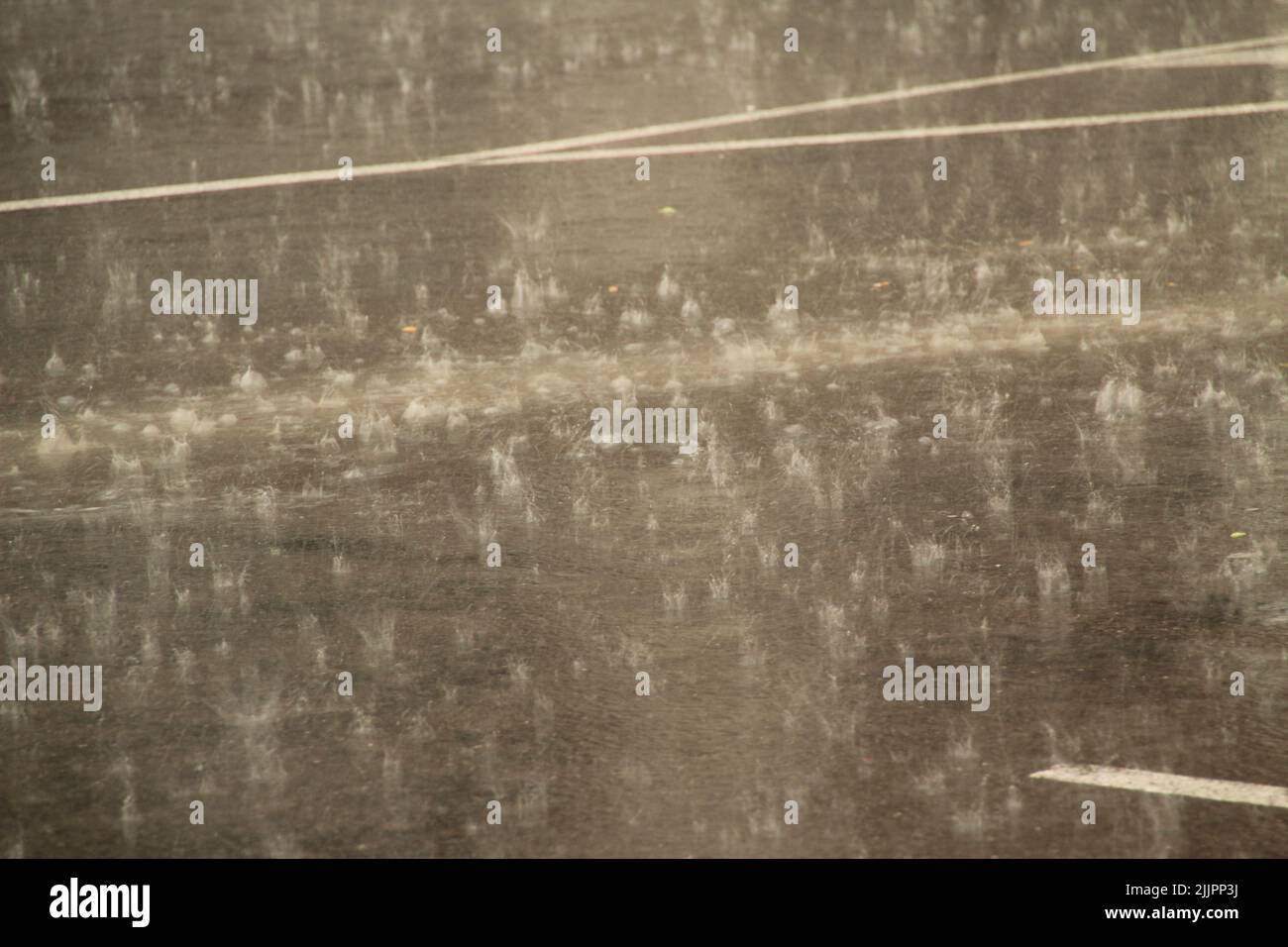 Una vista de las gotas de agua de lluvia sobre el asfalto en un día soleado Foto de stock