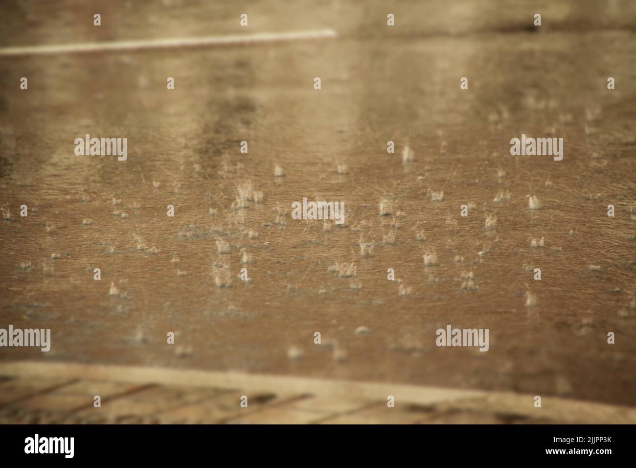 Una vista de las gotas de agua de lluvia sobre el asfalto en un día soleado Foto de stock