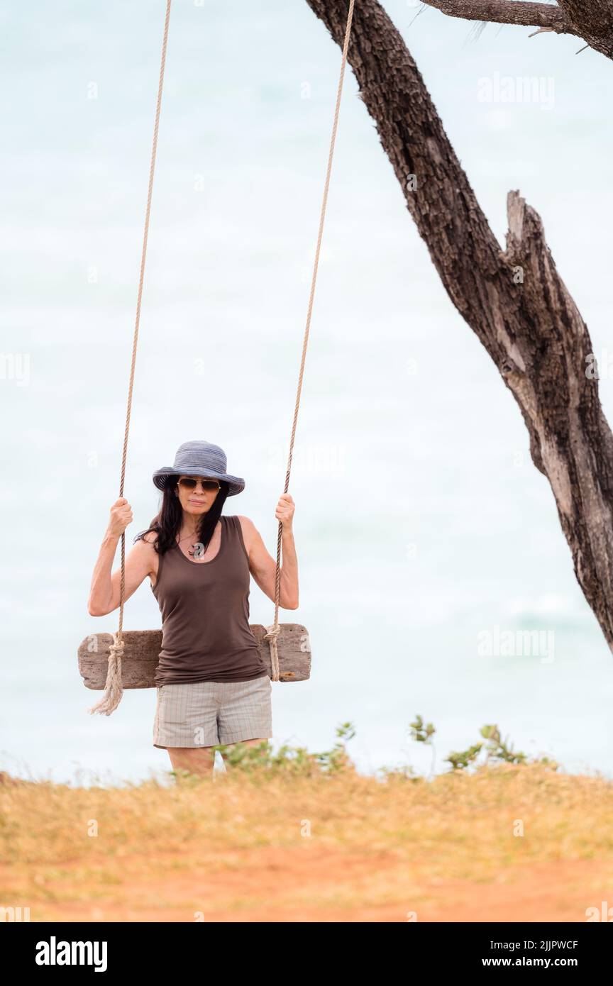 Una mujer preparándose para un columpio junto al mar en un día ventoso en Nhulunbuy, en la península de Gove, en el Territorio del Norte de Australia. Foto de stock