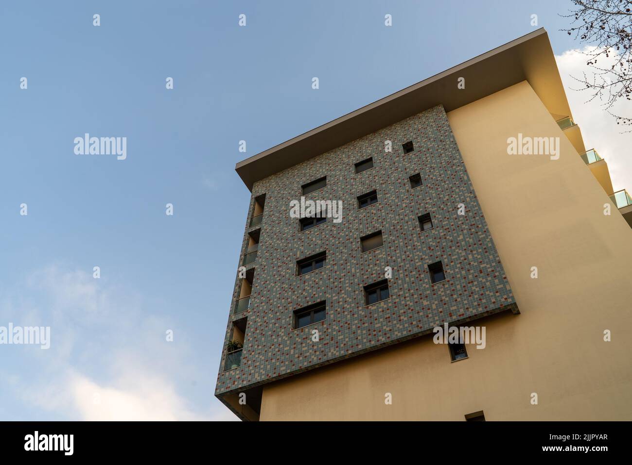 Plano de ángulo bajo con fachada de edificios beige y negro, con los últimos pisos bajo un cielo azul brillante Foto de stock