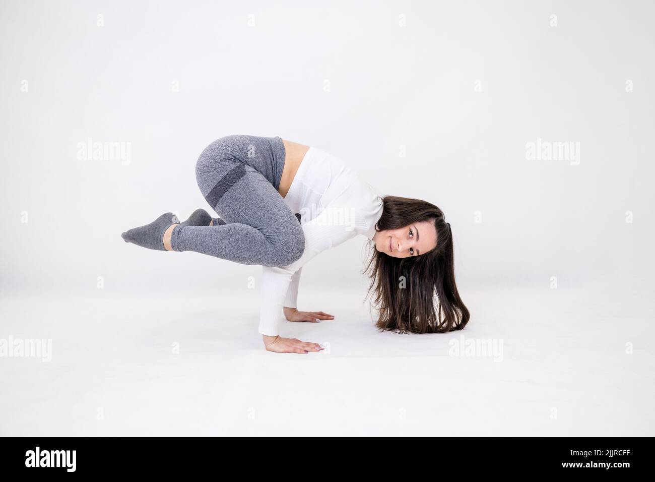 Una profesora de yoga haciendo movimientos acrobáticos mientras hace ejercicio Foto de stock