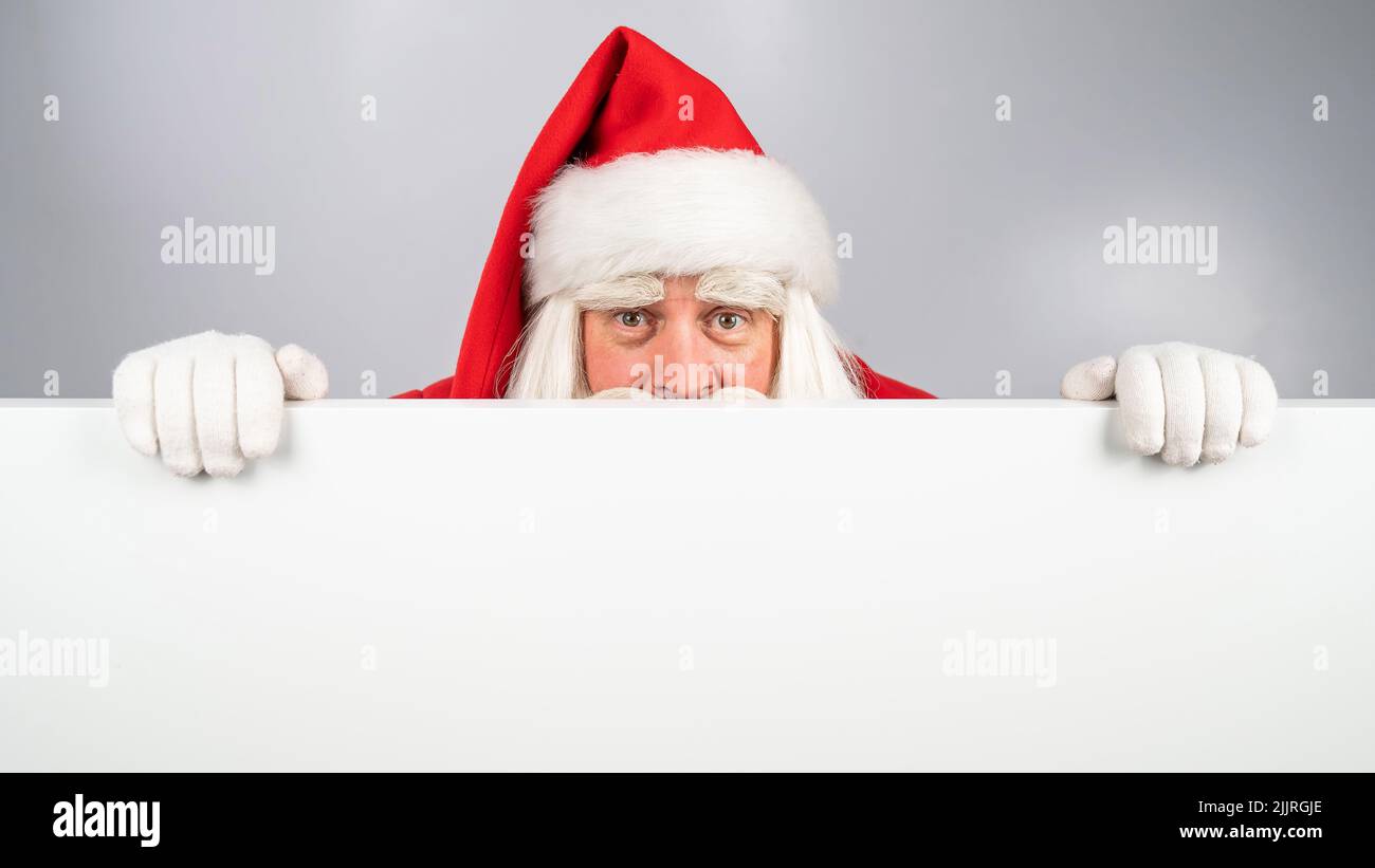 Santa Claus pule por detrás de un anuncio sobre un fondo blanco. Feliz  Navidad Fotografía de stock - Alamy