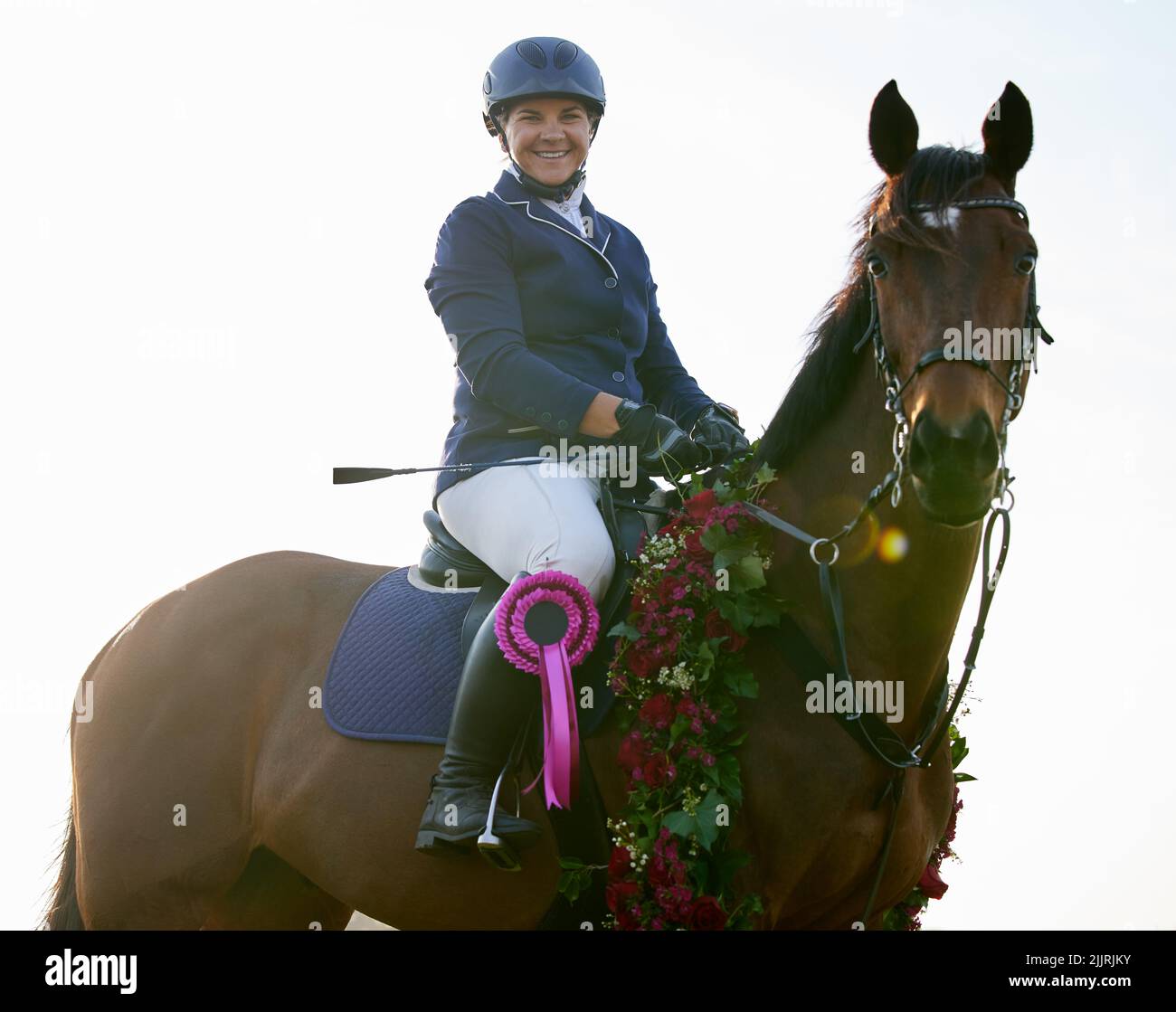 La victoria es nuestra. Una jinete joven atractiva sentada en sus caballos de vuelta en el círculo de ganadores. Foto de stock