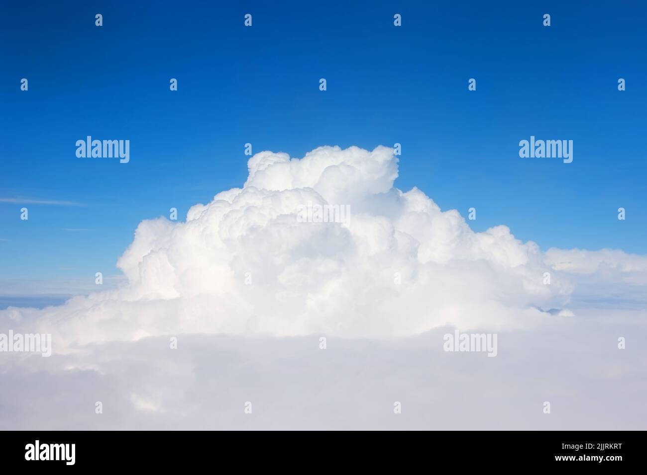 Una gigantesca nube cumulonimbus entre nubes de estratocumulus vistas desde un avión Foto de stock