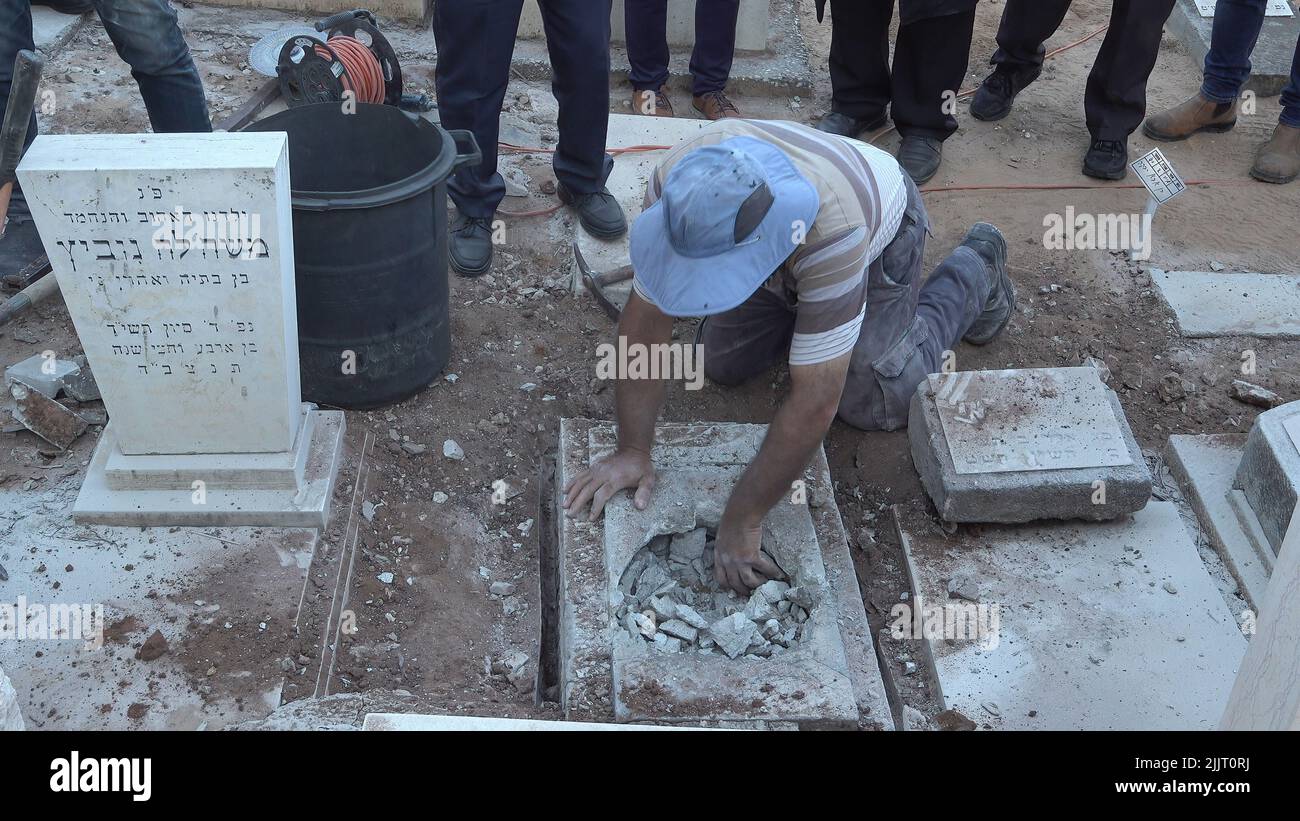 GIVATAYIM, ISRAEL - JULIO 27: Un trabajador abre la tumba de Yosef Melamed, un niño yemenita que murió en 1949, para recuperar una muestra de ADN en el Cementerio Nahalat Yitzhak el 27 de julio de 2022 en Givatayim, Israel. La tumba fue abierta para demostrar a la familia del niño que está enterrado allí y que no fue secuestrado y puesto para adopción. En la década de 1950s en Israel, los niños yemenitas desaparecieron, y los padres afirman que sus hijos fueron 'secuestrados' en el llamado asunto de los niños yemenitas. Crédito: Eddie Gerald/Alamy Live News Foto de stock