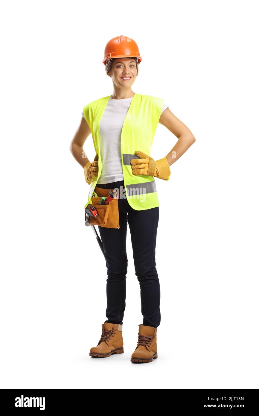 Retrato completo de una trabajadora de la construcción con un casco y un cinturón de herramientas aislado sobre fondo blanco Foto de stock