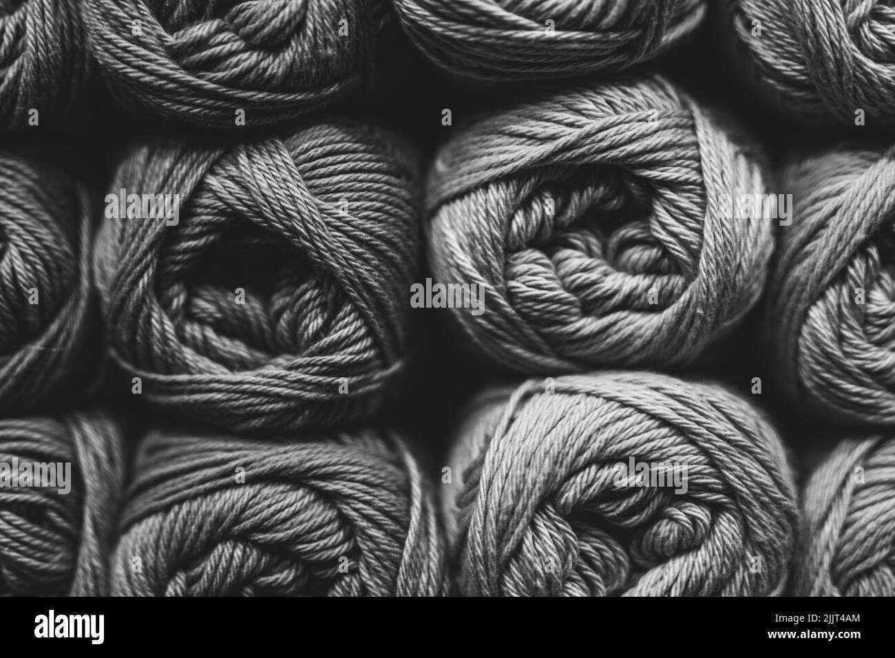 Una vista de primer plano de bolas de hilo en fondo blanco y negro, materiales para costura, tejer, aficiones Foto de stock