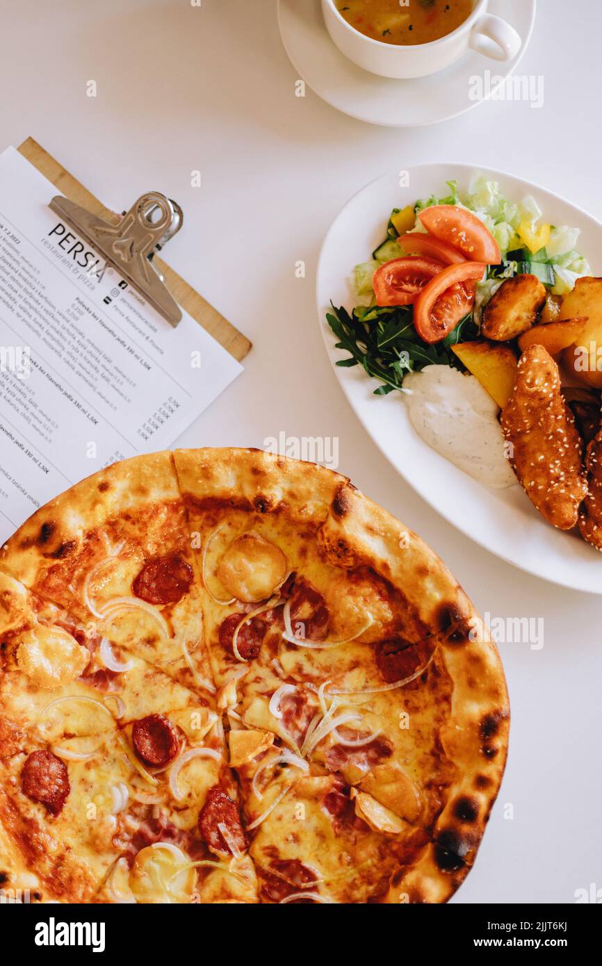 Una vista superior de la pizza, sopa y plato principal de nuggets de pollo con patatas al horno y verduras Foto de stock