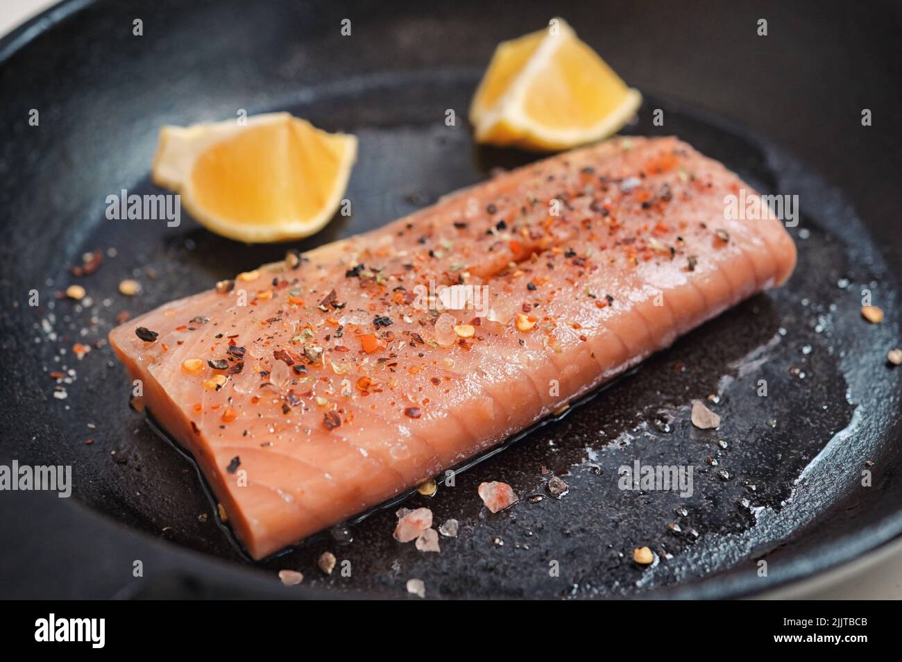 Filete de salmón asado en una sartén con rodajas de limón Foto de stock