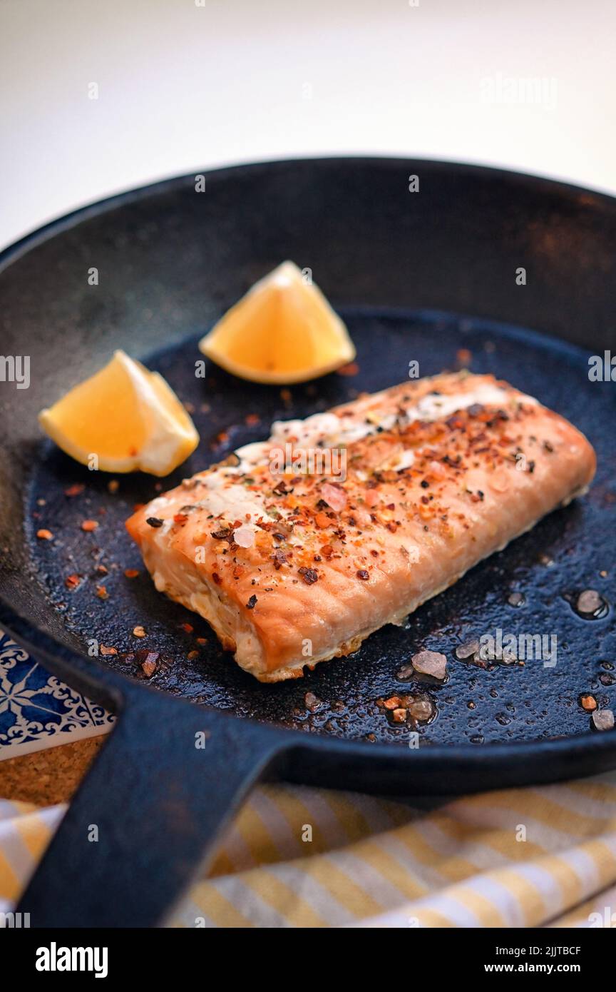 Filete de salmón asado en una sartén con rodajas de limón Foto de stock