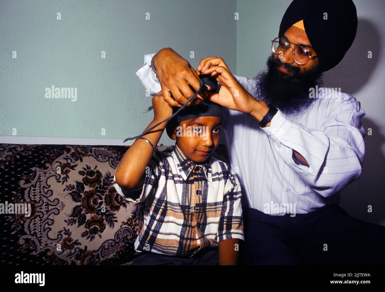 Padre Sikh Tying Su hijo de 7 años Patka Turban Southall Londres Inglaterra Foto de stock