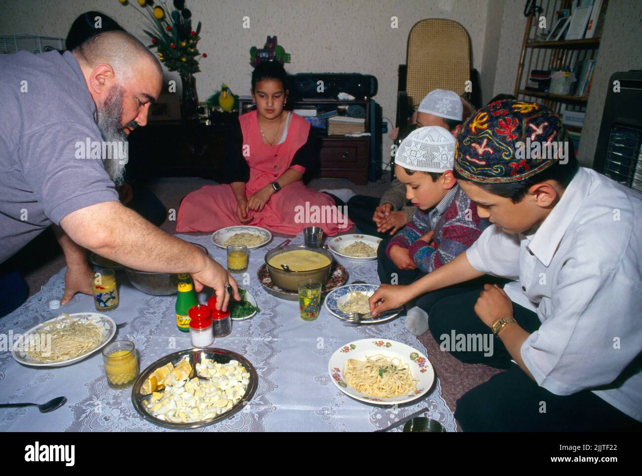 Familia Musulmana Rompiendo Rápido Después de Ramadán Sentándose en el piso Comer Clapton Londres Inglaterra Foto de stock