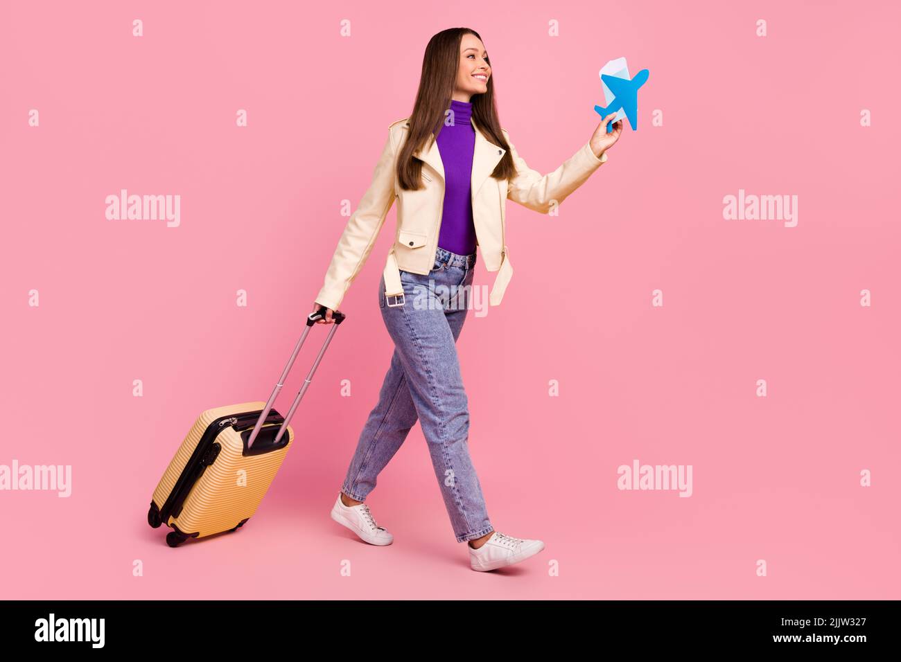 Foto de perfil larga de mujer joven con valise mantener plano look  promoción llevar chaqueta jeans botas aisladas sobre fondo de color rosa  Fotografía de stock - Alamy