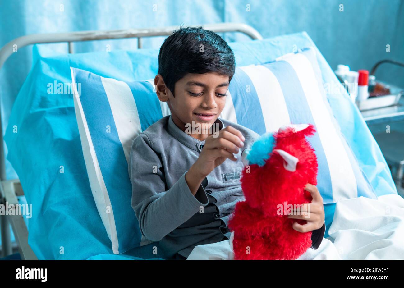 Niños enfermos felices jugando con oso de peluche en la sala del hospital - concepto de felicidad, estilo de vida de la infancia y tratamiento. Foto de stock