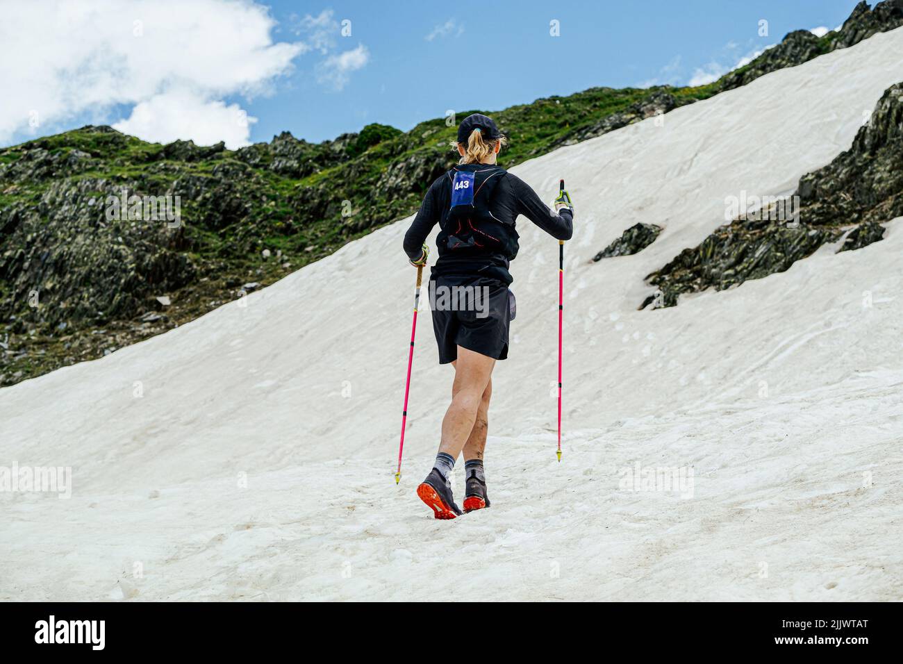 mujer atleta subiendo nieve cuesta arriba durante un ultra maratón Foto de stock