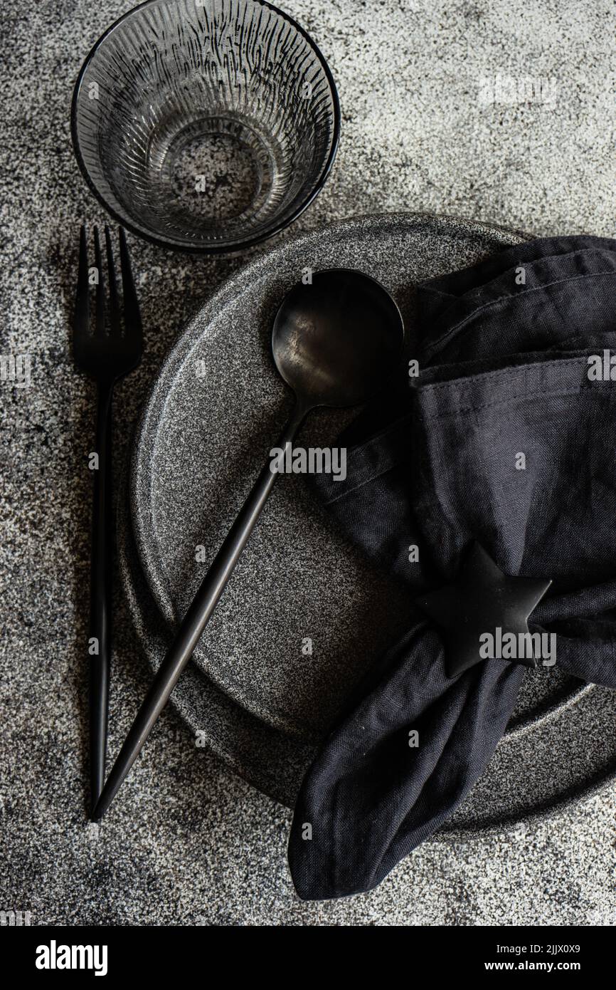 Vajilla negra minimalista sobre mesa de hormigón oscuro Fotografía