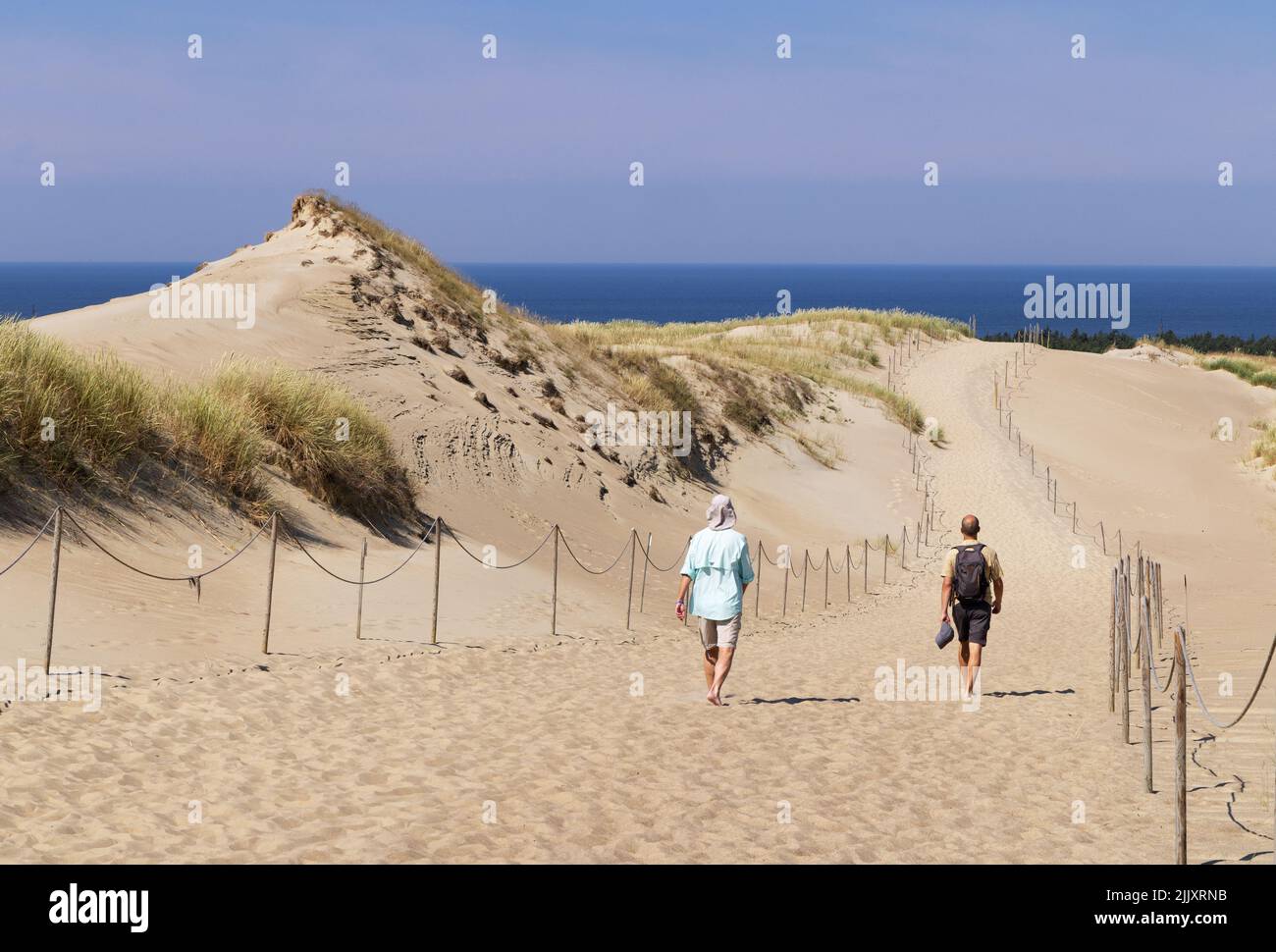 Turistas de Lituania - dos hombres caminando en las dunas de arena en verano, el Espada Curónica, costa de Lituania. Lituania Europa - ejemplo de viaje a Lituania Foto de stock