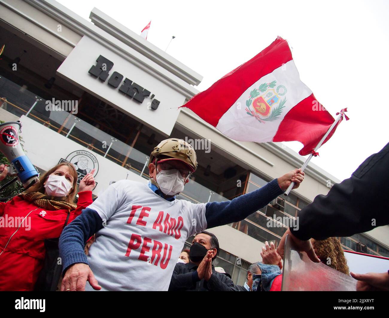 'Te quiero Perú' se puede leer en la camiseta de un manifestante mientras ondea una bandera cuando en el día de la independencia de Perú, cientos de personas se reúnen en las calles para protestar contra el presidente Pedro Castillo, acusado de varios actos de corrupción después del primer año de su gobierno. Foto de stock