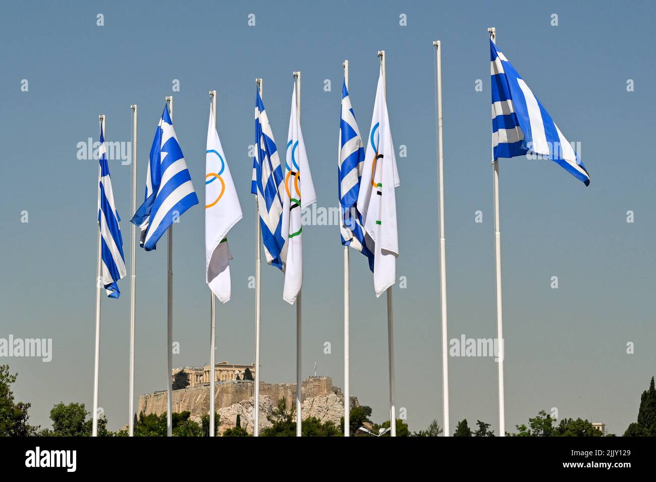 Atenas, Grecia - 2022 de mayo: Banderas nacionales griegas ondean en el histórico Estadio Olímpico de la ciudad con los Acroplis al fondo Foto de stock