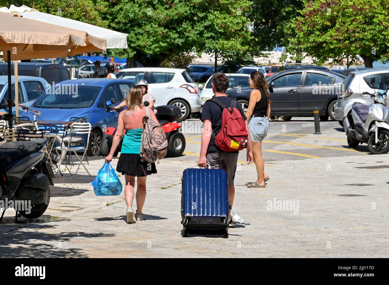 Corfú, Grecia - Junio de 2022: Dos jóvenes con equipaje haciendo su camino a la terminal de ferry en la ciudad de Corfú Foto de stock