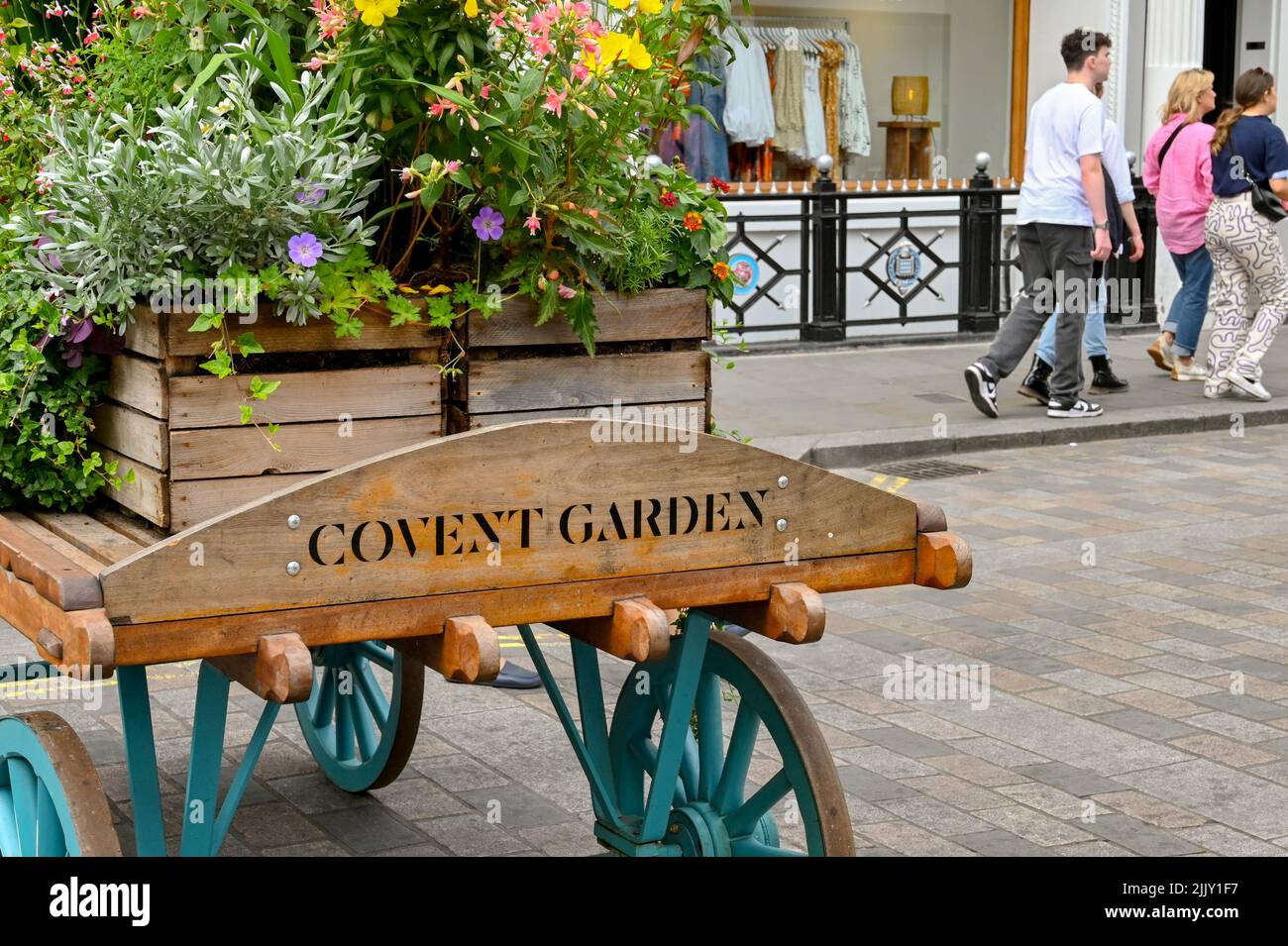 Londres, Reino Unido - Junio 2022: Cartel tallado en un viejo carro de madera con un florero en la parte superior que anuncia la entrada a Covent Garden Foto de stock