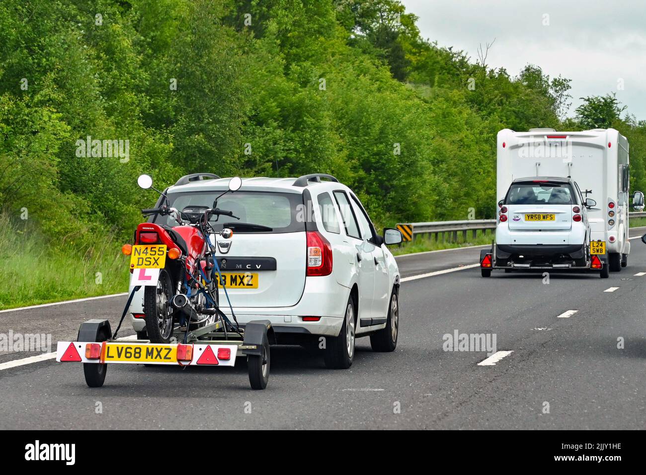Swindon, Inglaterra - Mayo de 2022: Coche tirando de un remolque cargado con una moto Foto de stock