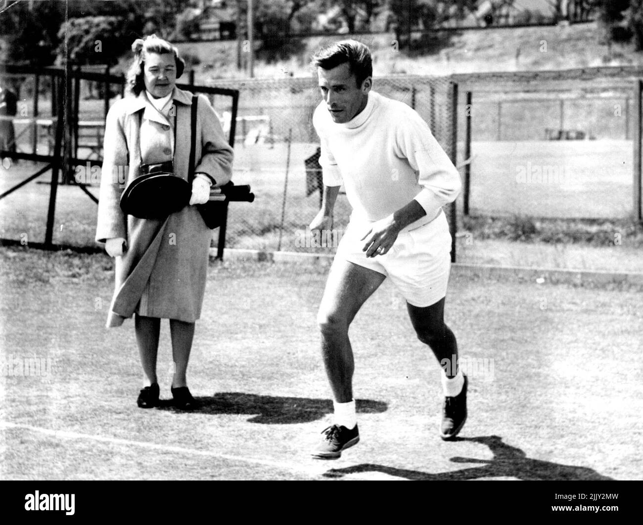 Supervisa el entrenamiento - la señora Parker sostiene las raquetas mientras que Frankie hace ejercicios de sprinting a la red en Kooyong (Melbourne). 21 de diciembre de 1947. Foto de stock