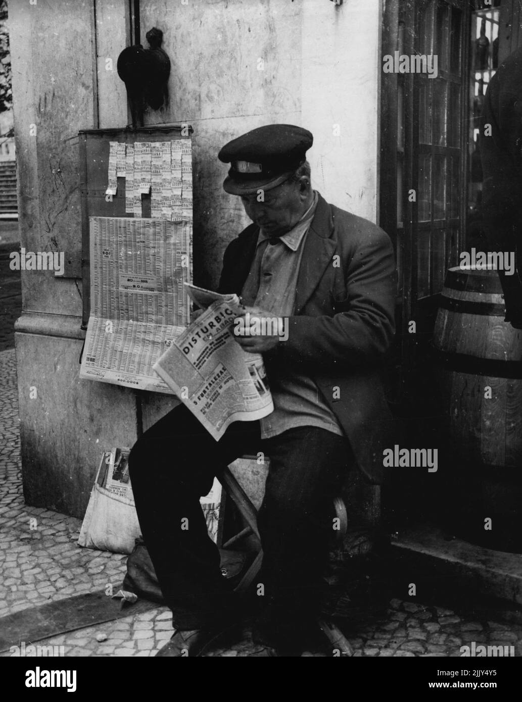 Lisboa 1952 -- Un vendedor típico de billetes de lotería estatal lee su diario. 27 de febrero de 1952. (Foto de Sequiera, prensa de cámara). Foto de stock