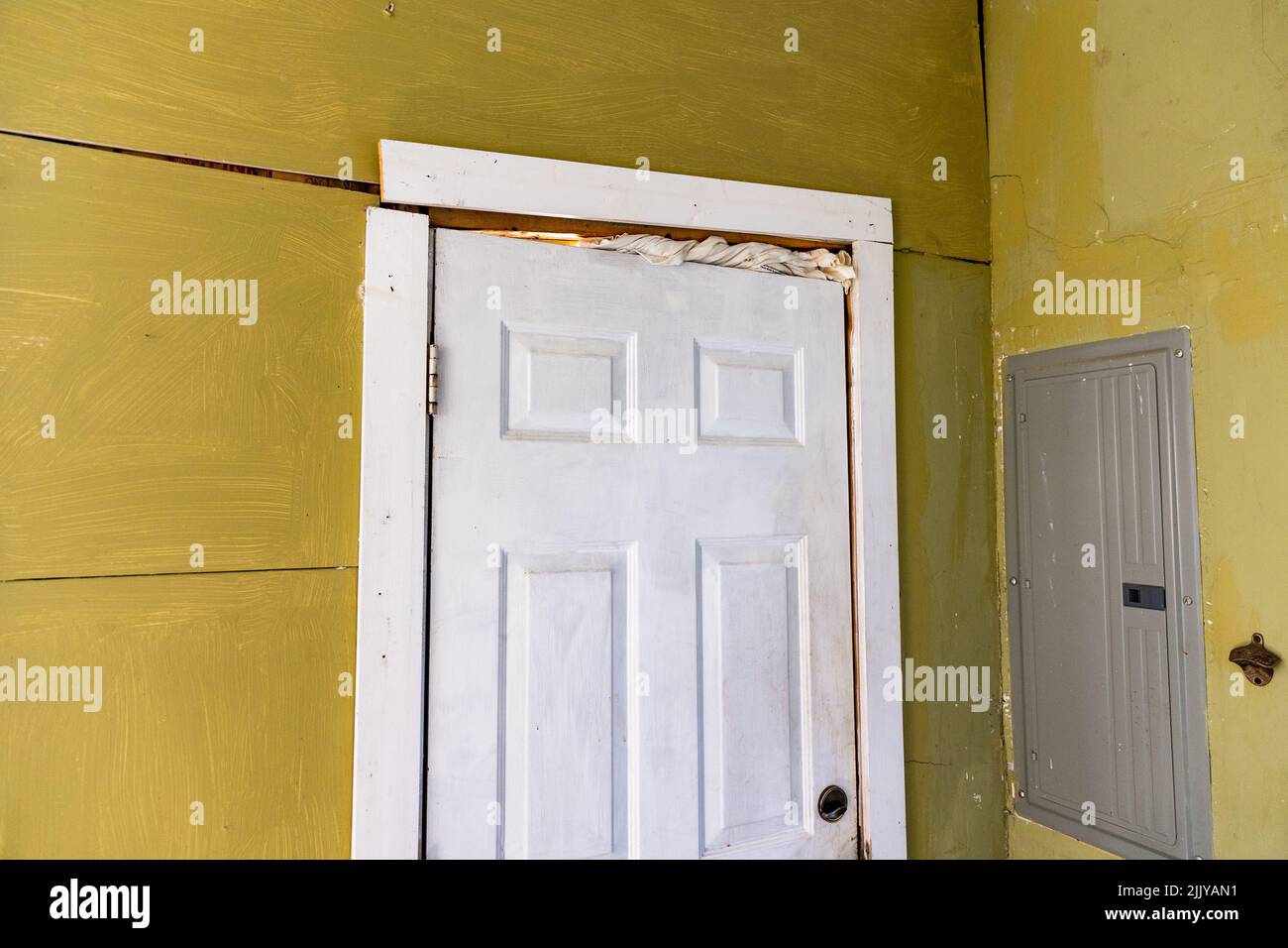 Marco de la puerta dañado y paredes agrietadas en la casa con problemas de cimentación Foto de stock