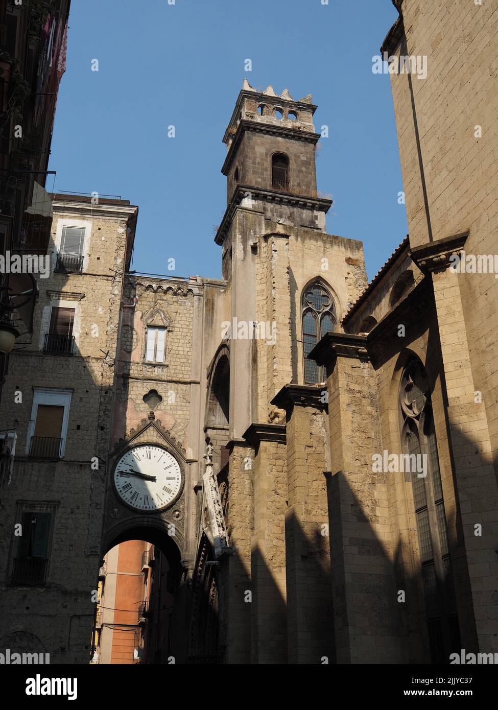 Iglesia en Nápoles con la pequeña torre y el reloj en un puente al otro lado de la calle. Nápoles, Campania, Italia Foto de stock